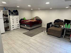 Bedroom featuring freestanding refrigerator, wood finish floors, and recessed lighting
