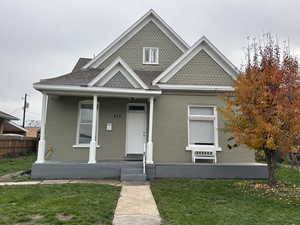 Victorian house featuring a front lawn, covered porch, and roof with shingles