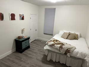 Bedroom with dark wood-style flooring and a paneled ceiling