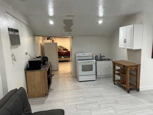 Kitchen featuring white appliances, white cabinetry, and a textured wall