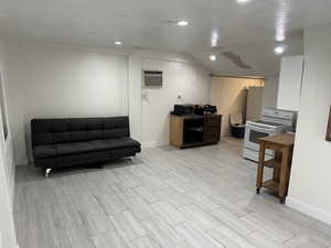 Kitchen featuring white range with electric cooktop, wood finish floors, recessed lighting, black microwave, and lofted ceiling