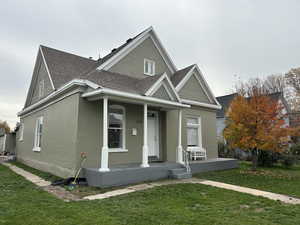 Victorian house with a shingled roof, a front lawn, covered porch, and brick siding