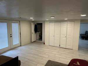 Below grade area with a textured ceiling, wood tiled floors, french doors, and recessed lighting
