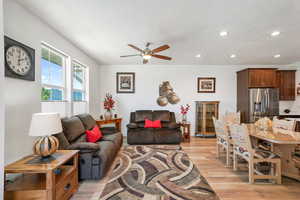 Living room featuring light wood-type flooring, a ceiling fan, a textured ceiling, and recessed lighting