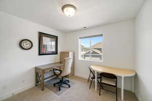 Office space with light colored carpet and a textured ceiling