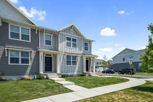 View of front facade with board and batten siding, a front lawn, a residential view, and a standing seam roof