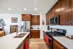 Kitchen with appliances with stainless steel finishes, recessed lighting, light wood finished floors, light stone counters, and a textured ceiling