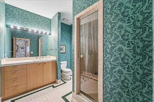 Bathroom with wallpapered walls, vanity, and a shower stall