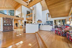 Living area with wooden ceiling, light wood-style floors, high vaulted ceiling, and a tiled fireplace