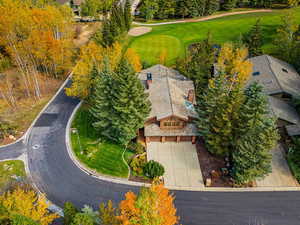 View from above of property with a golf course and a tree filled landscape