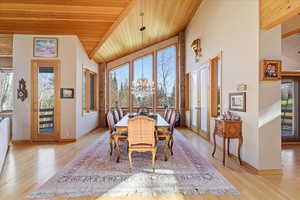 Dining space with wood ceiling, french doors, vaulted ceiling, a chandelier, and light wood-style floors