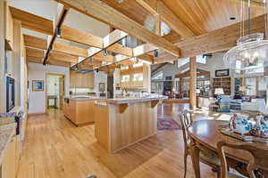 Kitchen featuring light brown cabinetry, a kitchen bar, light wood-style floors, open floor plan, and decorative light fixtures