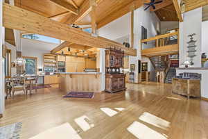 Living room with a wooden ceiling with exposed beams, light wood-type flooring, stairs, high vaulted ceiling, and a ceiling fan