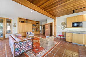 Living area with dark tile patterned flooring, recessed lighting, and a wood ceiling with exposed beams
