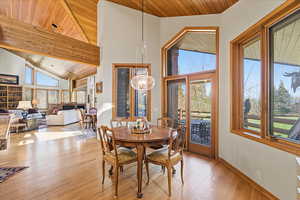Dining room with wooden ceiling, high vaulted ceiling, and light wood-style flooring