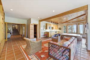 Living room with stairway, recessed lighting, light tile patterned flooring, and a wooden ceiling with exposed beams