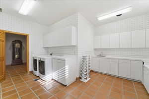 Laundry room featuring cabinet space, light tile patterned floors, and washer and clothes dryer