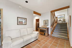Tiled living room with stairs, beam ceiling, and recessed lighting