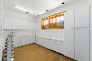 Kitchen with white cabinetry, light countertops, wallpapered walls, and light tile patterned floors