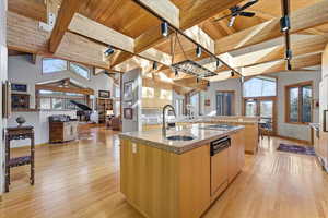 Kitchen featuring track lighting, ceiling fan, a wood ceiling with exposed beams, light wood-style flooring, and light stone countertops