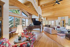 Living area with a fireplace, light wood-type flooring, wood ceiling, and ceiling fan
