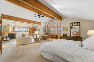 Carpeted bedroom featuring multiple windows, a fireplace with raised hearth, and ceiling fan