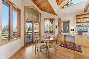 Dining room featuring wooden ceiling, a chandelier, high vaulted ceiling, and light wood-style flooring
