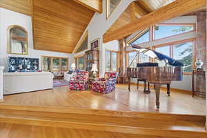 Living room featuring high vaulted ceiling, light wood-style flooring, and a wooden ceiling with exposed beams