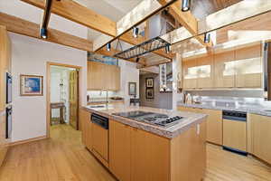 Kitchen featuring light brown cabinets, an island with sink, light wood-type flooring, stainless steel electric cooktop, and dishwasher