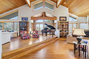 Living room with light wood-style floors, high vaulted ceiling, and a wooden ceiling with exposed beams