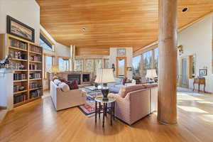 Living area featuring wood ceiling, high vaulted ceiling, healthy amount of natural light, a glass covered fireplace, and light wood-type flooring