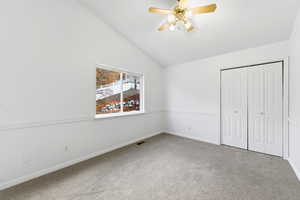 Unfurnished bedroom with carpet, a closet, lofted ceiling, and ceiling fan