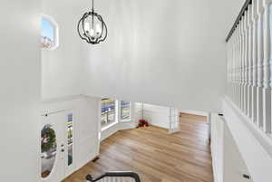 Foyer entrance with a towering ceiling, light wood-style floors, and a chandelier