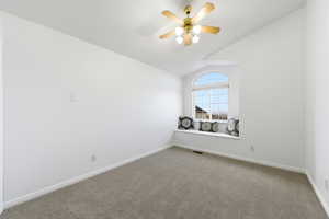 Spare room with lofted ceiling, carpet, and ceiling fan