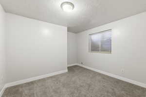 6th Bedroom, featuring a textured ceiling and carpet