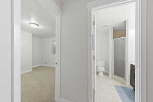 3/4 bathroom with a shower stall, a textured ceiling, light colored carpet, and vanity