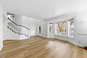 Foyer entrance with stairs and light wood-type flooring, bay window