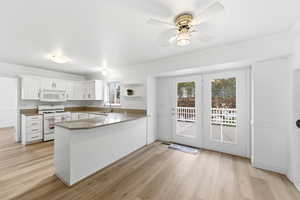 Kitchen dining and bar,with white appliances, crown molding, white cabinetry, a peninsula, and light wood finished floors