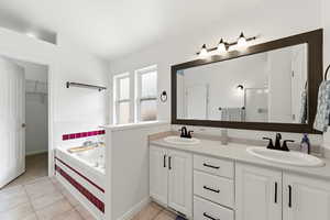 Primary Suite, Full bathroom with double vanity, light tile patterned flooring, a bath, and a walk in closet