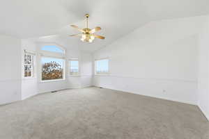 Carpeted primary suite featuring lofted ceiling and a ceiling fan