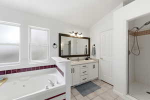 Primary Bathroom featuring double vanity, a shower stall, a jetted tub, light tile patterned flooring, and lofted ceiling