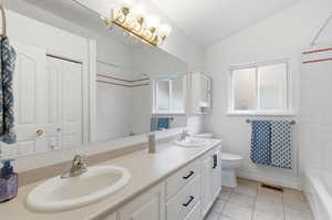 Full bath featuring shower / bathtub combination, double vanity, light tile patterned floors, and lofted ceiling