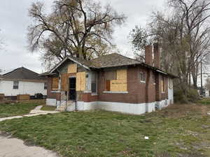 Bungalow-style home with brick siding, a front lawn, a chimney, and entry steps