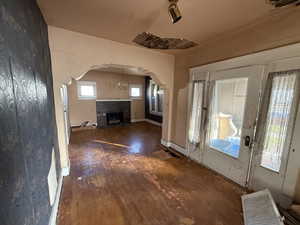 Foyer with arched walkways, a fireplace, dark wood finished floors, and a chandelier