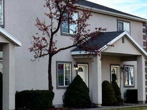 View of front of house with stucco siding, a front yard, and roof with shingles