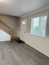 Foyer with stairway, wood finished floors, ornamental molding, and a textured ceiling