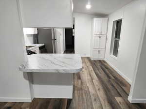 Kitchen featuring white cabinetry, light countertops, a peninsula, dark wood finished floors, and appliances with stainless steel finishes