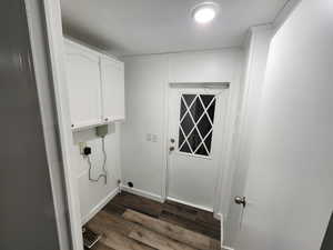 Laundry area featuring a textured ceiling, dark wood-style floors, and cabinet space