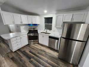 Kitchen with a peninsula, appliances with stainless steel finishes, white cabinets, light countertops, and a textured ceiling
