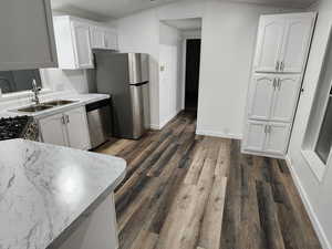 Kitchen with white cabinetry, light countertops, dishwasher, dark wood finished floors, and crown molding